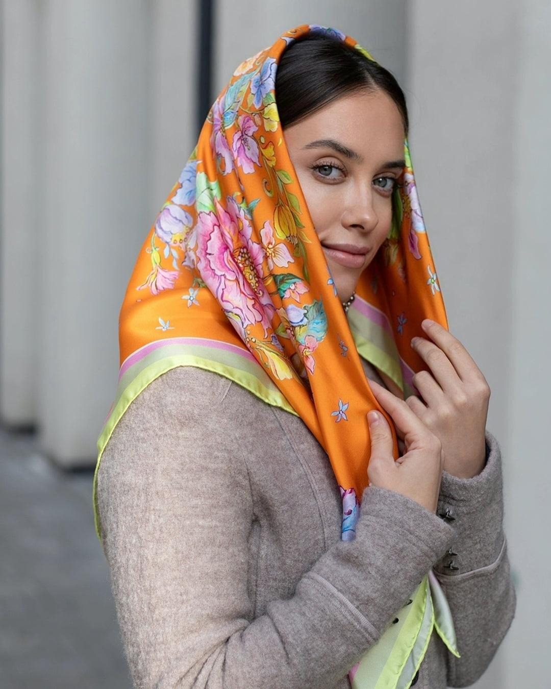 Das Mädchen trägt einen exquisiten orangefarbenen Seidenschal mit Blumenmuster, ein vielseitiges Accessoire für stilvolle Looks.