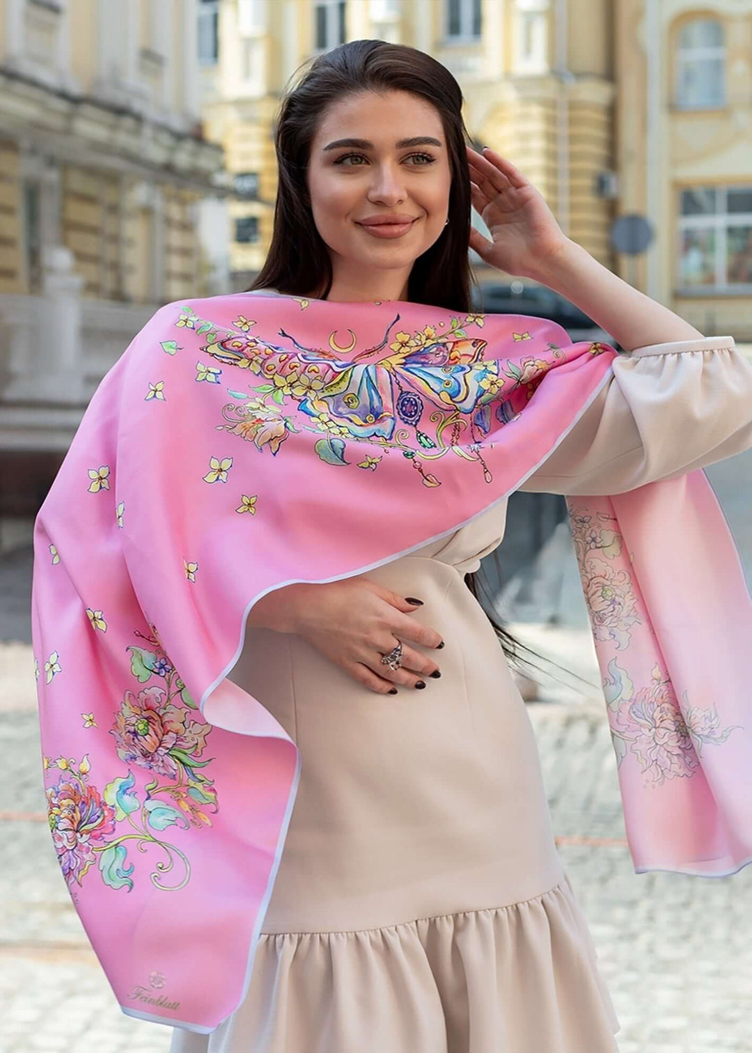Frau trägt den Designer-Seidenschal Geschenk fuer Frauen Seidenschal Schmetterling in Rosa  luxuriöser Seidenschal mit Schmetterlingsmotiv und floralen Details, elegant über die Schultern gelegt, Design von Iryna Feinblatt.