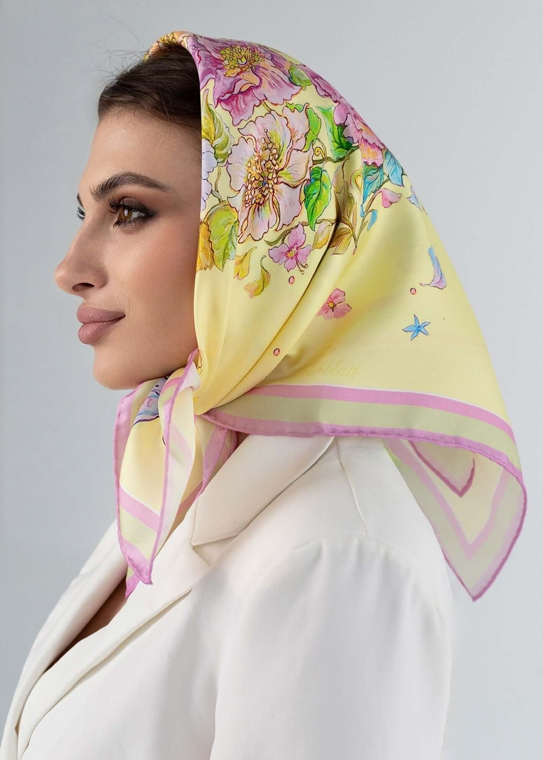 Geschenk fuer Frauen – gelbes Seidentuch mit Blumen in elegantem Design, getragen von einer Frau.