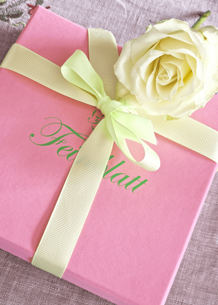 Geschenkverpackung von Feinblatt: Rosafarbene Box mit zartgrüner Schleife und weißer Rose