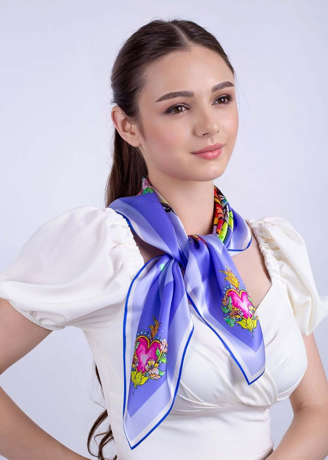 Elegant woman wearing Designer Silk Scarf Pretty in Blue Lila, featuring floral and horse designs, 70x70cm.