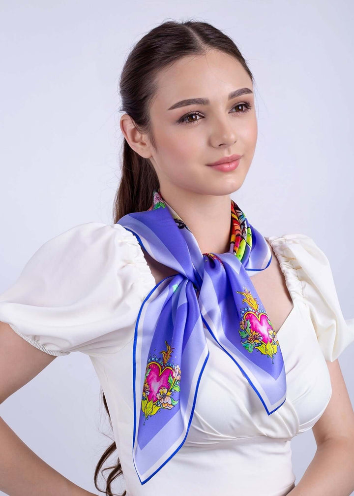 Elegant woman wearing Designer Silk Scarf Pretty in Blue Lila, featuring floral and horse designs, 70x70cm.