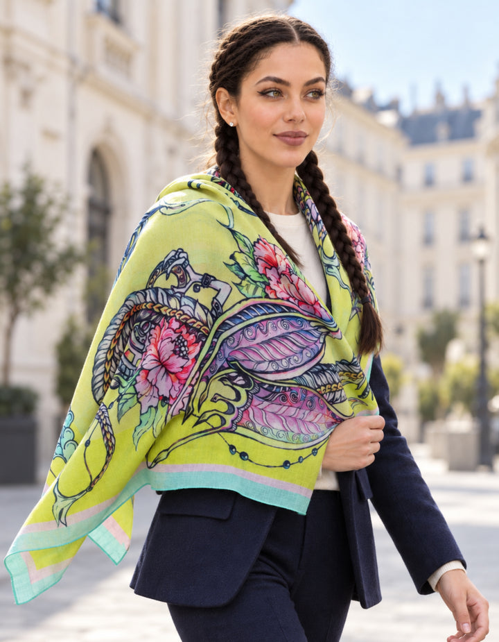 Frau trägt den gelben Designer-Kaschmirschal Dragons von Iryna Feinblatt beim Spaziergang durch eine helle europäische Stadt über den Schultern.
