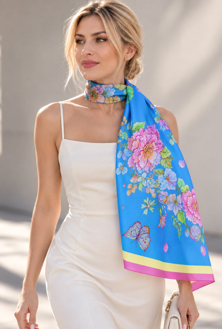 Blauer Designer-Seidenschal von Feinblatt mit floralem Motiv und Schmetterling, elegant zum weißen Kleid getragen