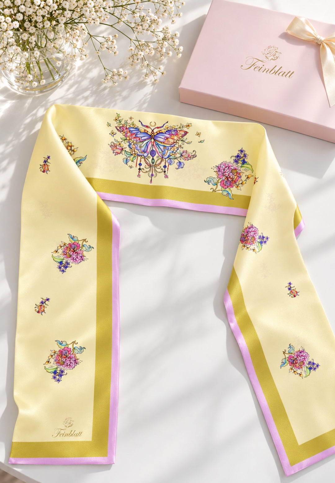 Gelber Designer-Seidenschal mit Schmetterlings- und Blumenmotiv neben Feinblatt Geschenkbox