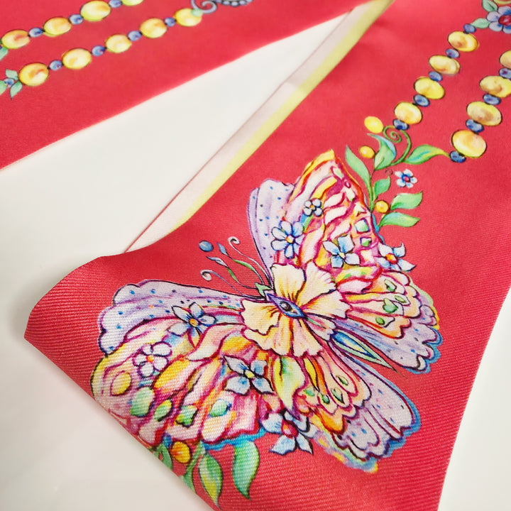 Makroaufnahme eines Designer Seidenschals in Koralle mit detailreichem Schmetterlingsmotiv und floralen Schmuckornamenten, luxuriöse reine Seide mit feiner Struktur und hochwertigem Kunstdruck von Iryna Feinblatt