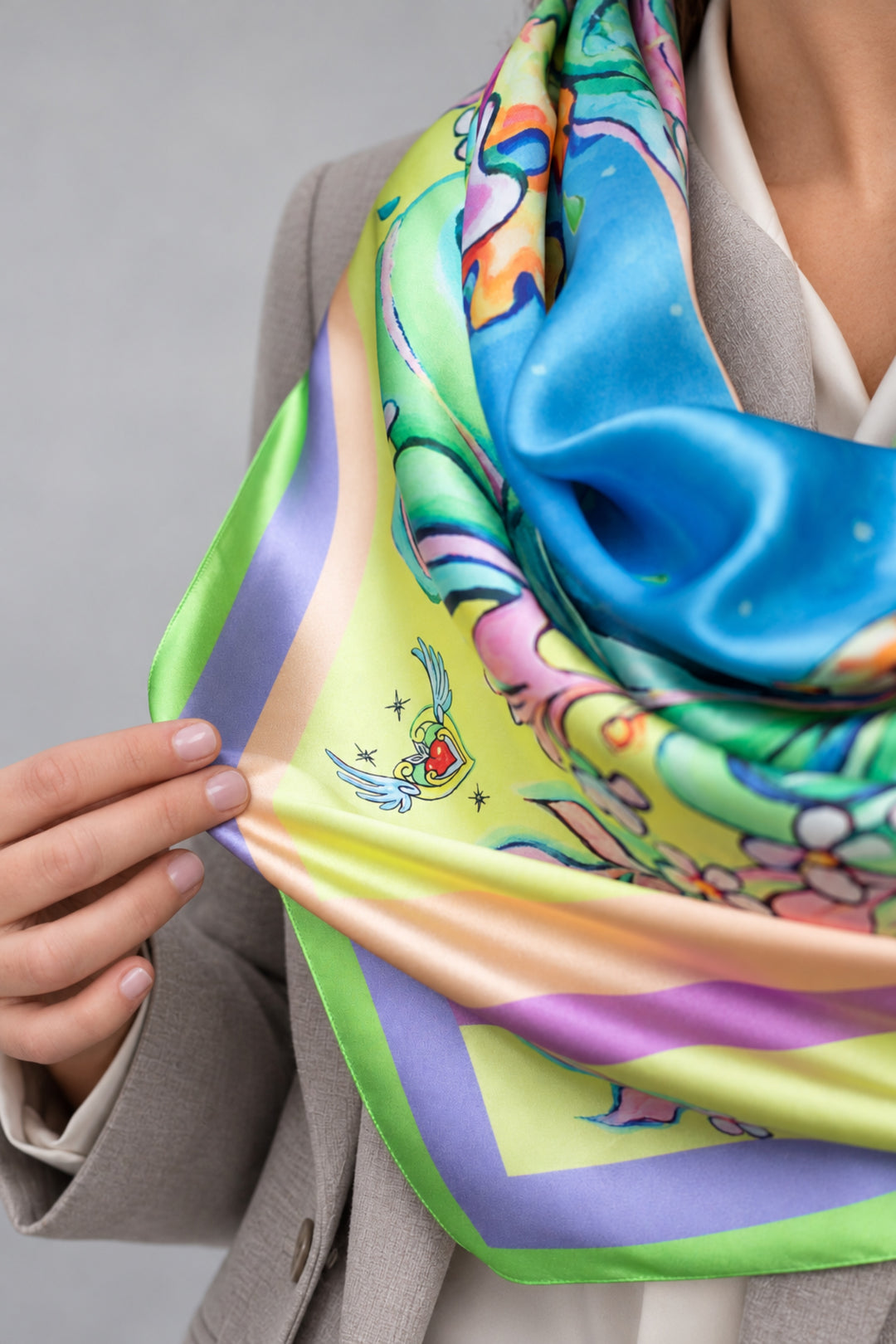 Detailaufnahme des Designer-Seidenschals Leoparden Multicolor aus Seidensatin mit grünem Rand und kleinem Herzmotiv.
