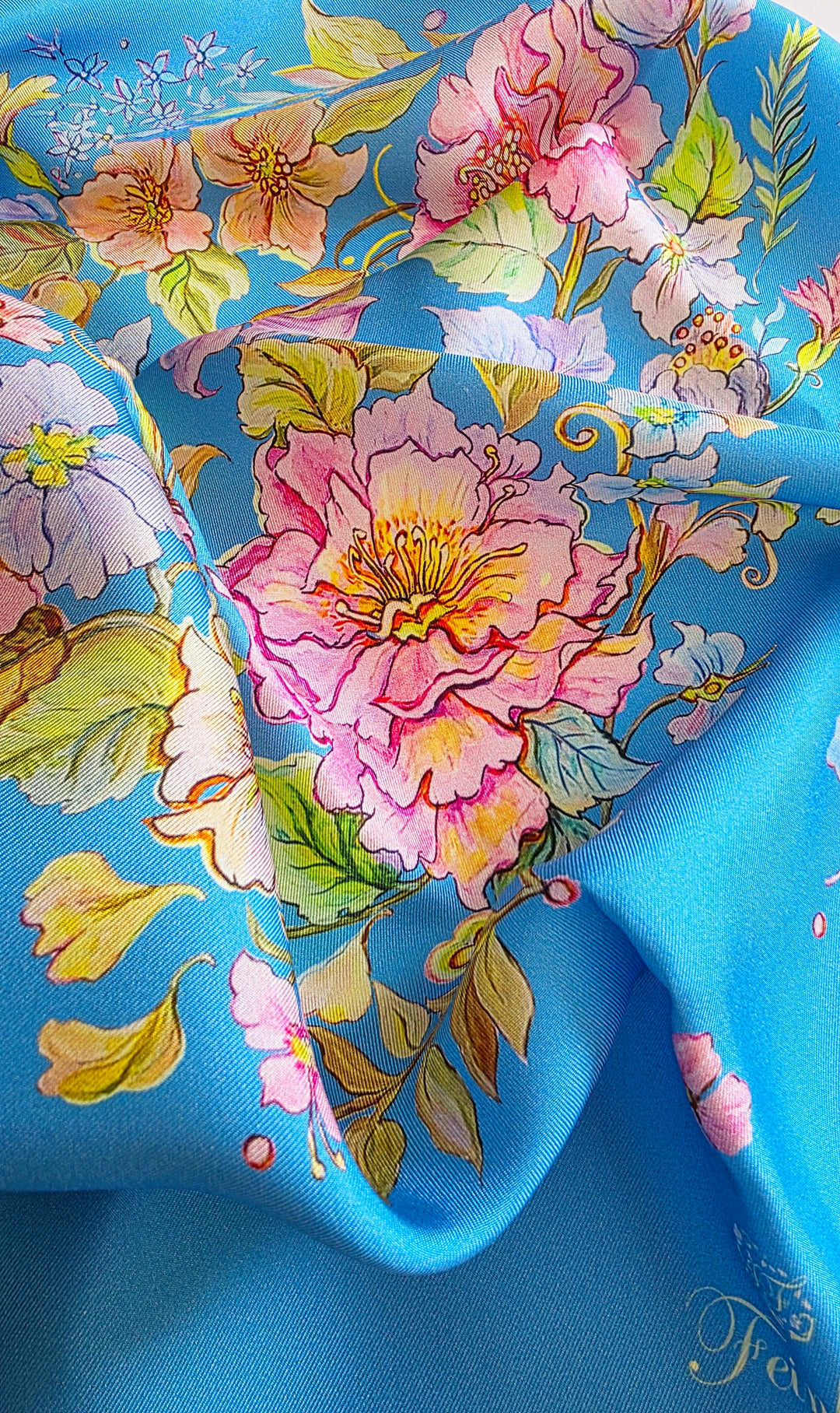 Detailaufnahme eines blauen Designer-Seidenschals von Feinblatt mit rosa Blüten, feinen Blättern und sichtbarer Webstruktur der Seide.