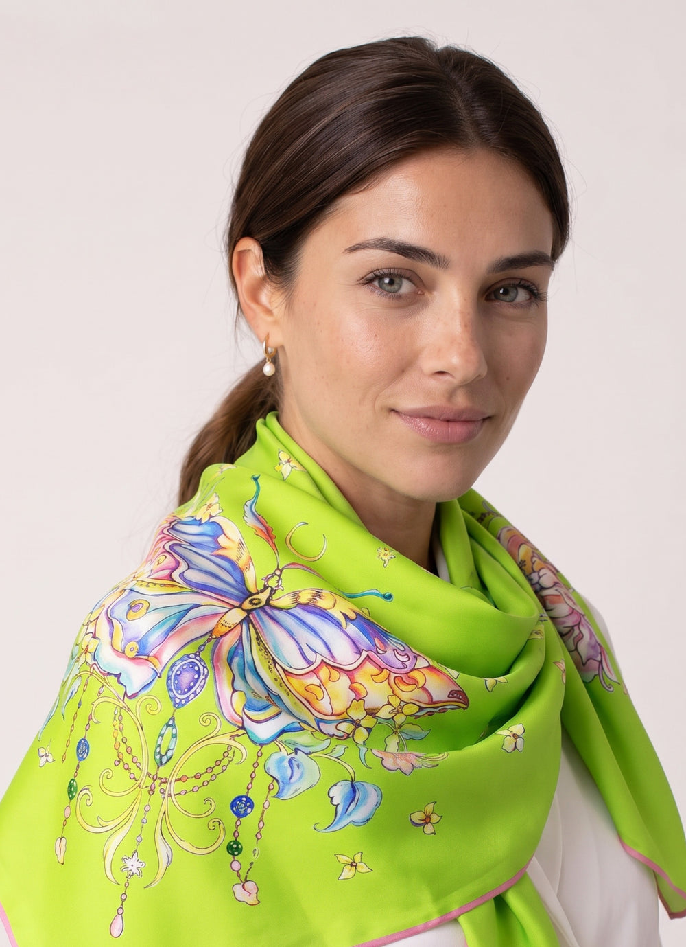 Elegante Frau mit limegrünem Designer Seidenschal Lime Butterfly aus Seide mit farbigem Schmetterlingsmotiv und floralen Details von Feinblatt.