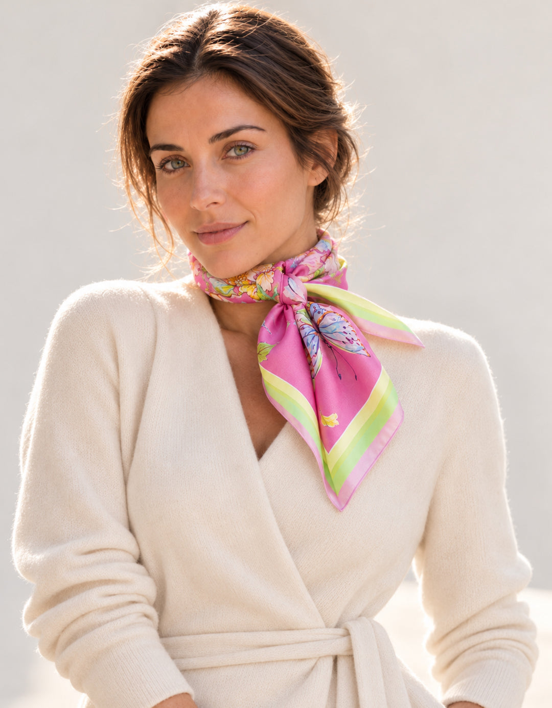 Porträt einer Frau mit rosa Designer-Seidenschal von Feinblatt mit Blumen und Schmetterling, seitlich am Hals gebunden.