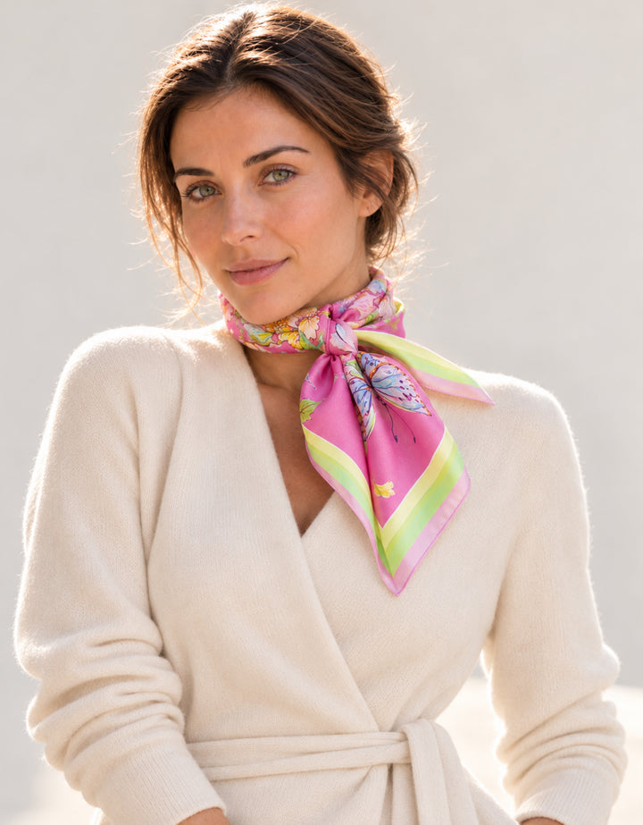 Porträt einer Frau mit rosa Designer-Seidenschal von Feinblatt mit Blumen und Schmetterling, seitlich am Hals gebunden.