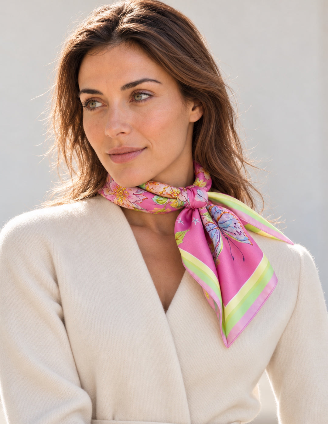 Frau trägt den Designer-Seidenschal Herz aus Blumen in Rosa/Fuchsia, 65 × 65 cm, aus Twill-Seide, elegant seitlich am Hals gebunden.